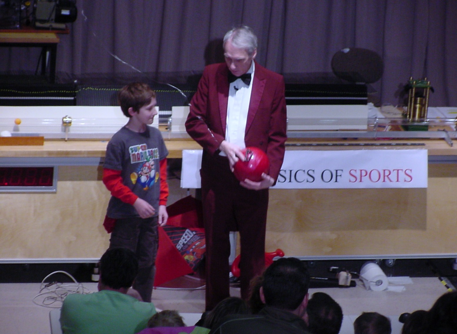 Man shows boy a ball on stage
