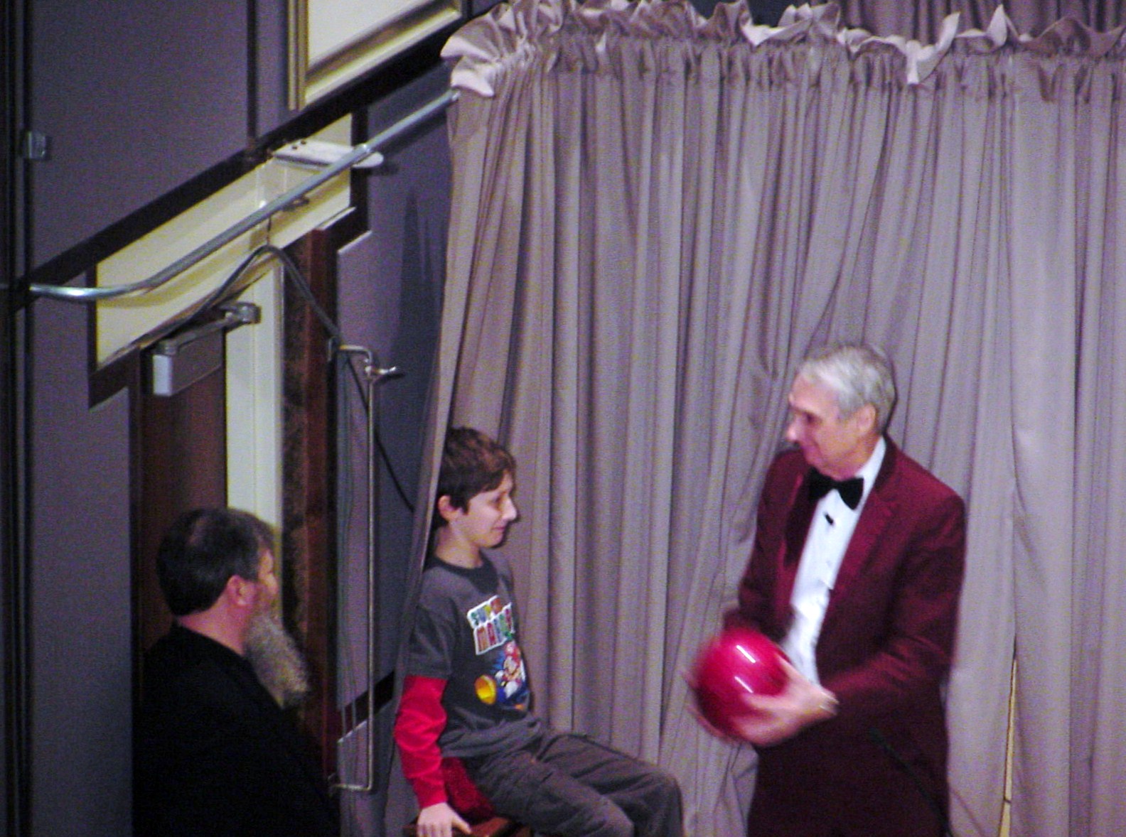 Man shows boy a ball on stage