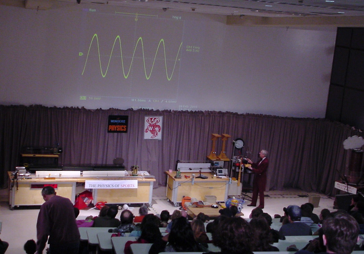 Man on stage presenting sound waves