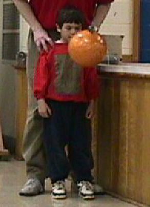 Boy standing in front of bowling ball suspended from the ceiling