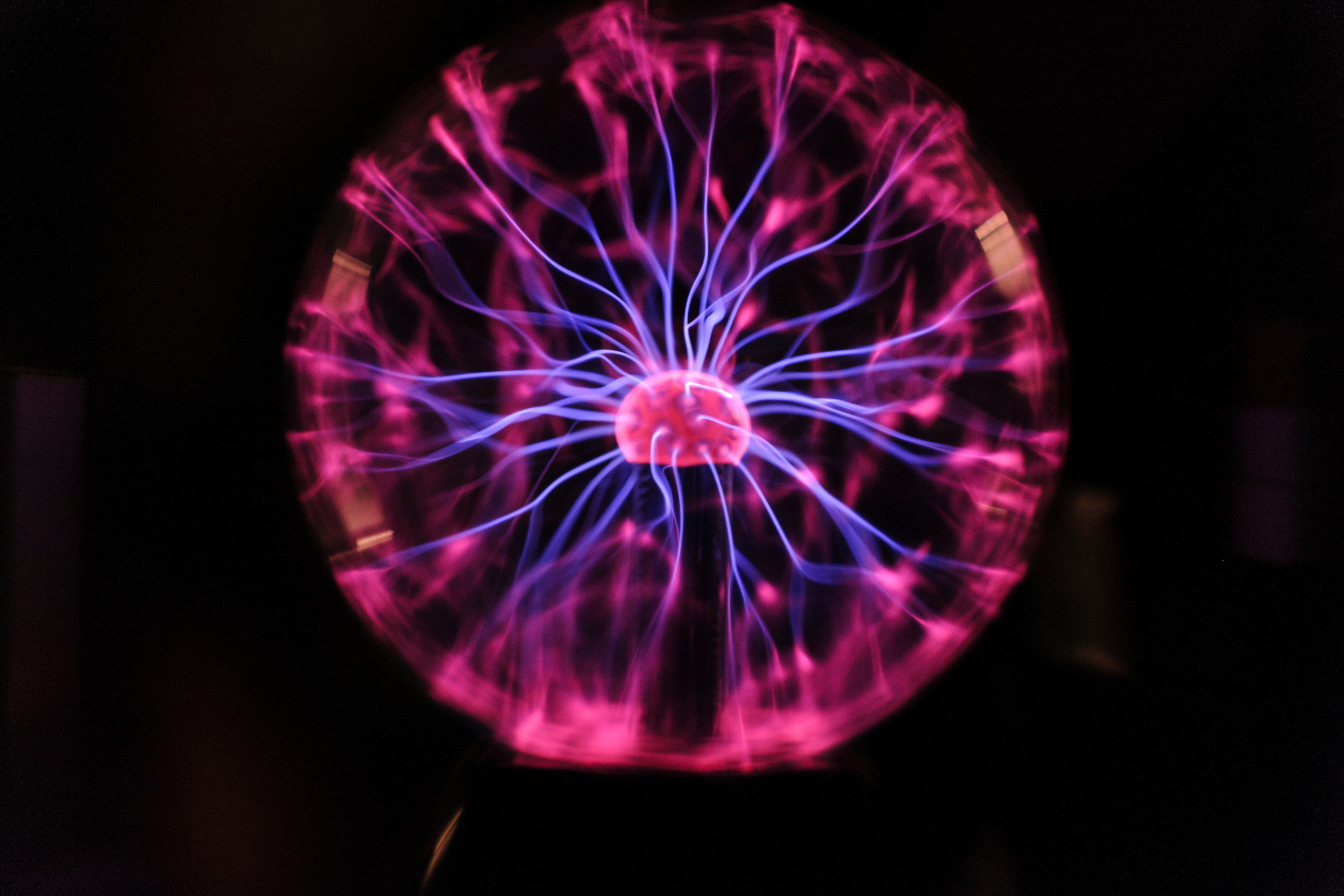 The conduction of electrons radiates from a Tesla coil within a plasma ball during a Wonders of Physics show