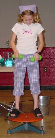 Girl standing on spinning device with weights by her side