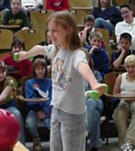 Girls stands on spinning device holding weights away from her body