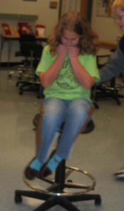 Girl Spinning in chair with arms close to her chest